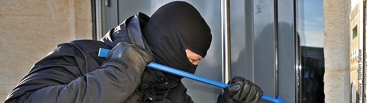 Einbrecher mit Kuhfuß vor Fenster