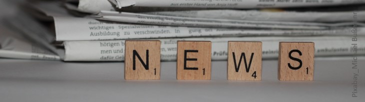 Scrabble-Buchstaben bilden das Wort "News" vor einem Zeitungsstapel