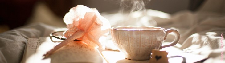 Teetasse neben Stift mit rosa Papierrose