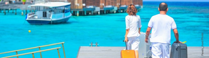 Mann und Frau mit Koffern auf Steg am Meer