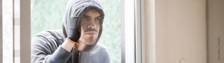 Einbrecher schaut durchs Fenster